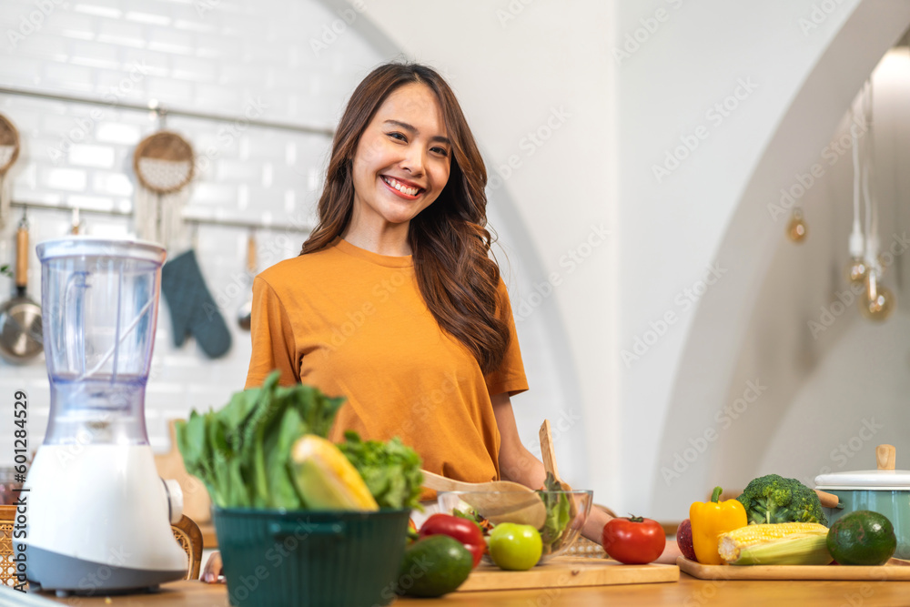 Portrait of beauty body slim healthy asian woman having fun cooking and preparing cooking vegan food healthy eat with fresh vegetable salad in kitchen at home.Diet concept.Fitness, wellness, healthy