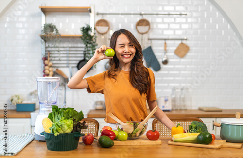 Portrait of beauty body slim healthy asian woman having fun cooking and preparing vegan food healthy eat with fresh vegetable salad, apple in kitchen at home.Diet concept.Fitness and healthy food