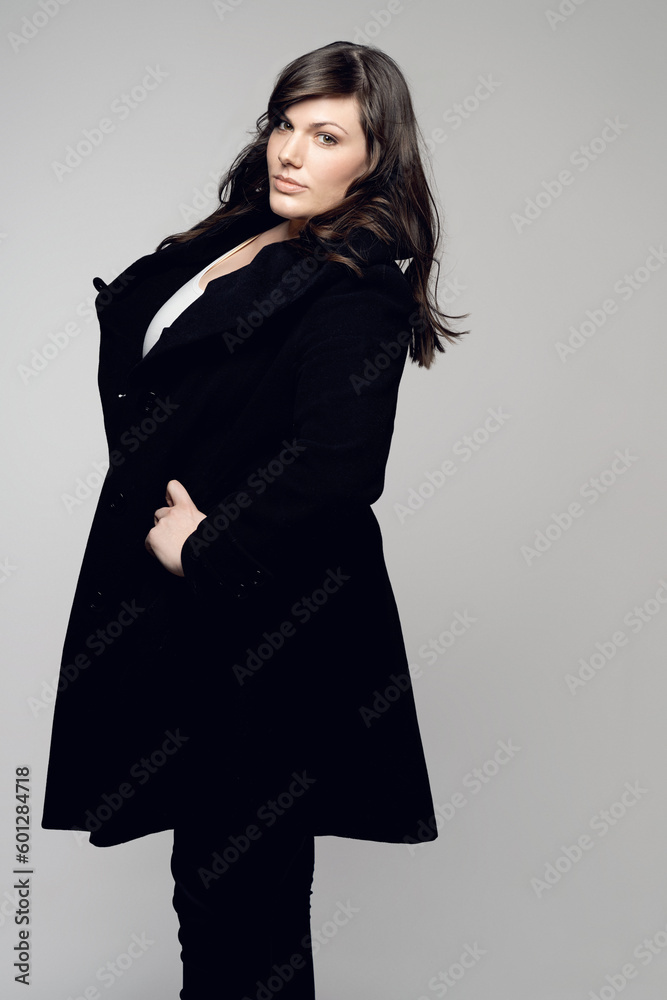 Woman, fashion and portrait of plus size model posing in winter clothing against grey studio background. Isolated female person standing with stylish black coat or warm fashionable clothes for beauty Woman, fashion and portrait of plus size model posing in winter clothing against grey studio background. Isolated female person standing with stylish black coat or warm fashionable clothes for beauty