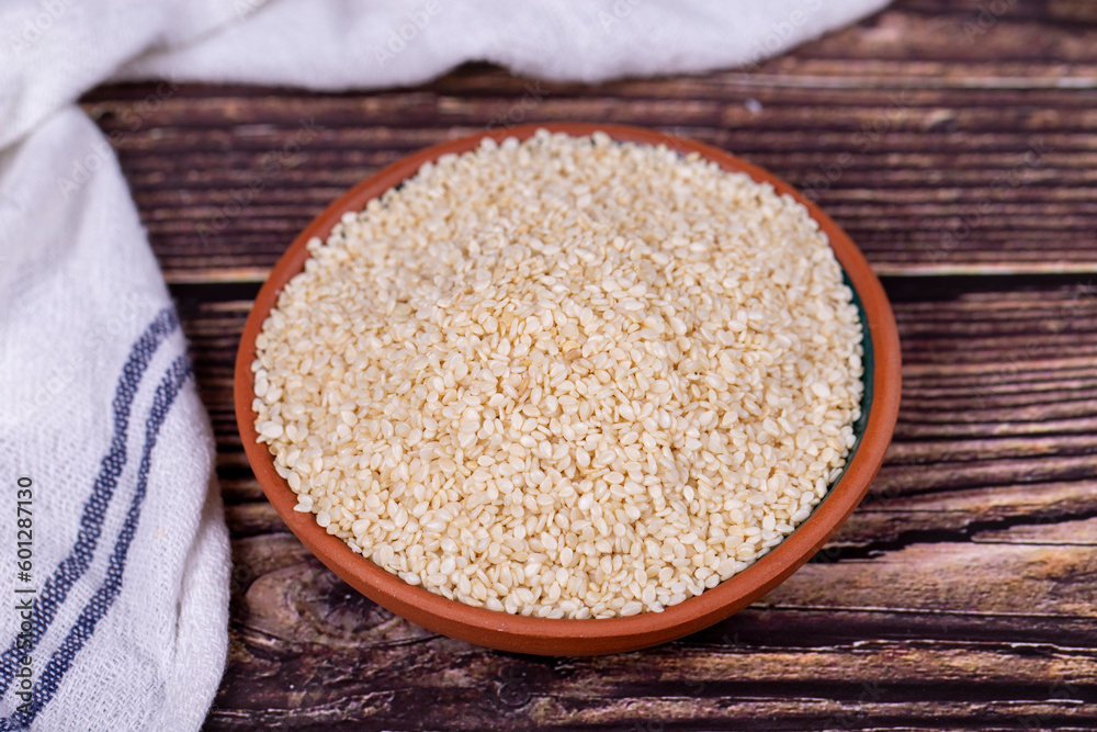 Sesame seeds on wooden background. Organic White Sesame seeds (Sesamum indicum) in Earthen bowl Sesame seeds on wooden background. Organic White Sesame seeds (Sesamum indicum) in Earthen bowl