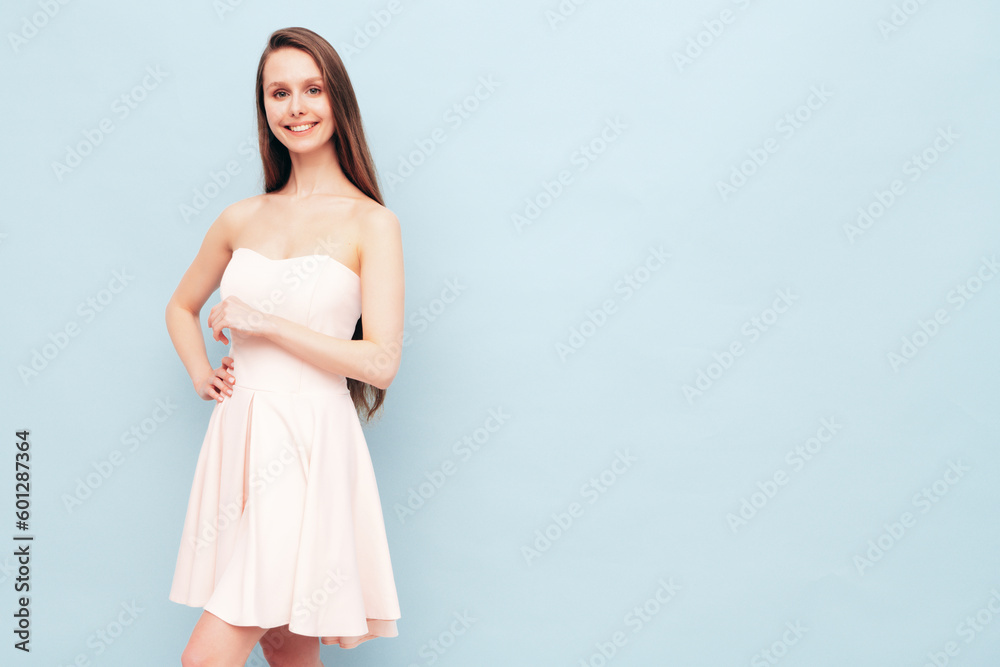 Portrait of young winsome woman in romantic attire pretty smiling on blue background. Slim female in pure pink dress posing in studio. Cheerful model. Isolated. Long hair Portrait of young winsome woman in romantic attire pretty smiling on blue background. Slim female in pure pink dress posing in studio. Cheerful model. Isolated. Long hair