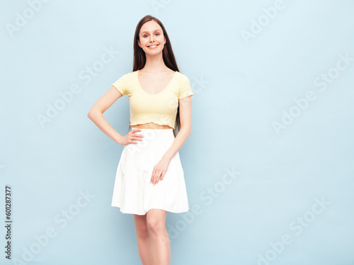 Image portrait of optimistic woman in yellow t-shirt and white skirt. Carefree stylish model with long hair. Smiling female posing in studio. Isolated. Looks delightful and cute. Slim