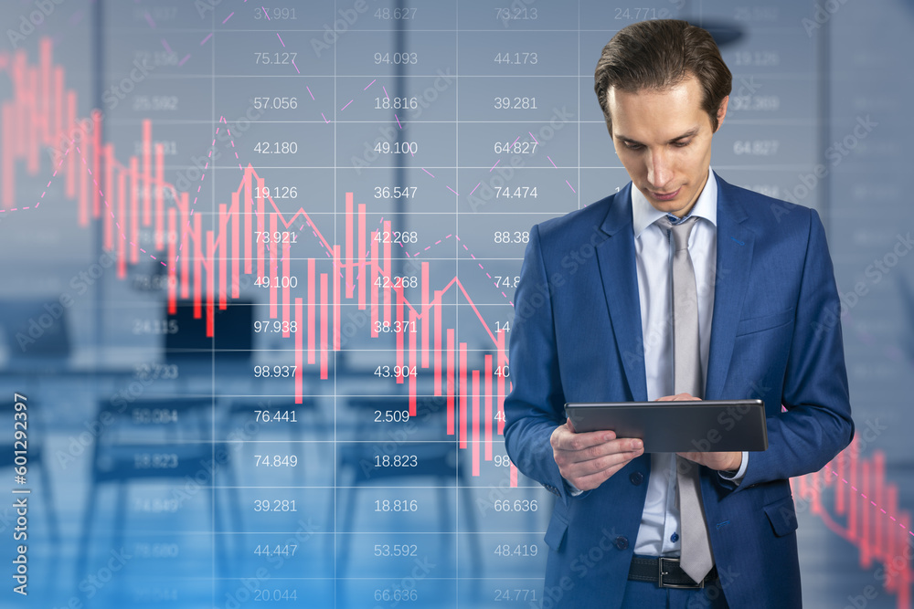 Attractive thoughtful european businessman using tablet with falling red business graph grid on blurry office interior background. Crisis, recession and stock market concept. Double exposure. Attractive thoughtful european businessman using tablet with falling red business graph grid on blurry office interior background. Crisis, recession and stock market concept. Double exposure.