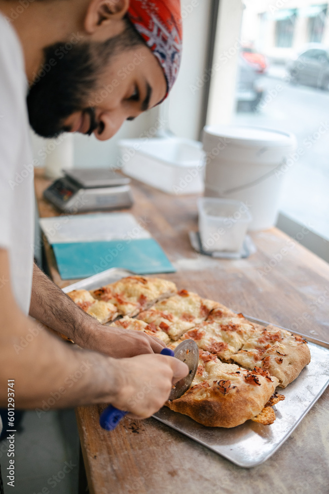 Arabic pizza maker cutting dough with cutter