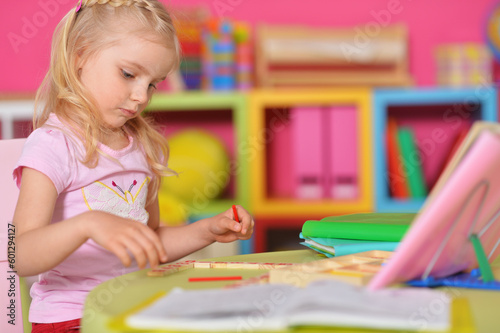 Little cute girl studying at the table at home