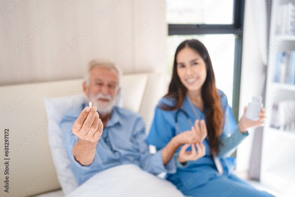 Obraz premium Smiling young nurse in hospital and health care center giving routine medications to happy and cheerful senior patient lying and sitting on bed while having a fun conversation