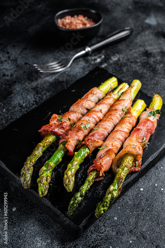 Asparagus Baked with bacon and spices. Black background. Top view