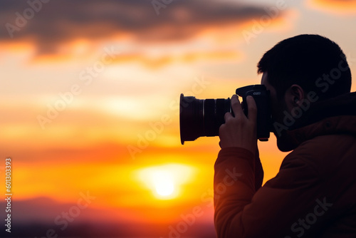 An unrecognizable man holding a camera and taking a photo of a stunning sunset representing photography and creativity,