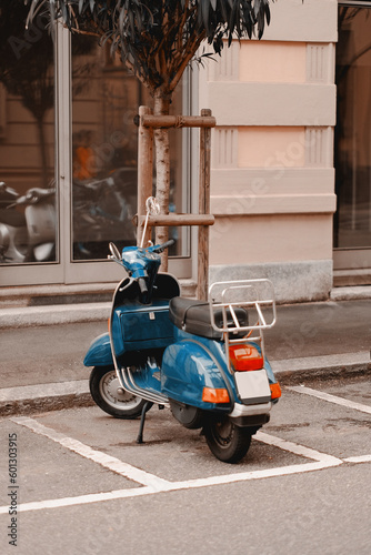 A vintage delivery scooter parked on the street. Modern bike to reach the destination.