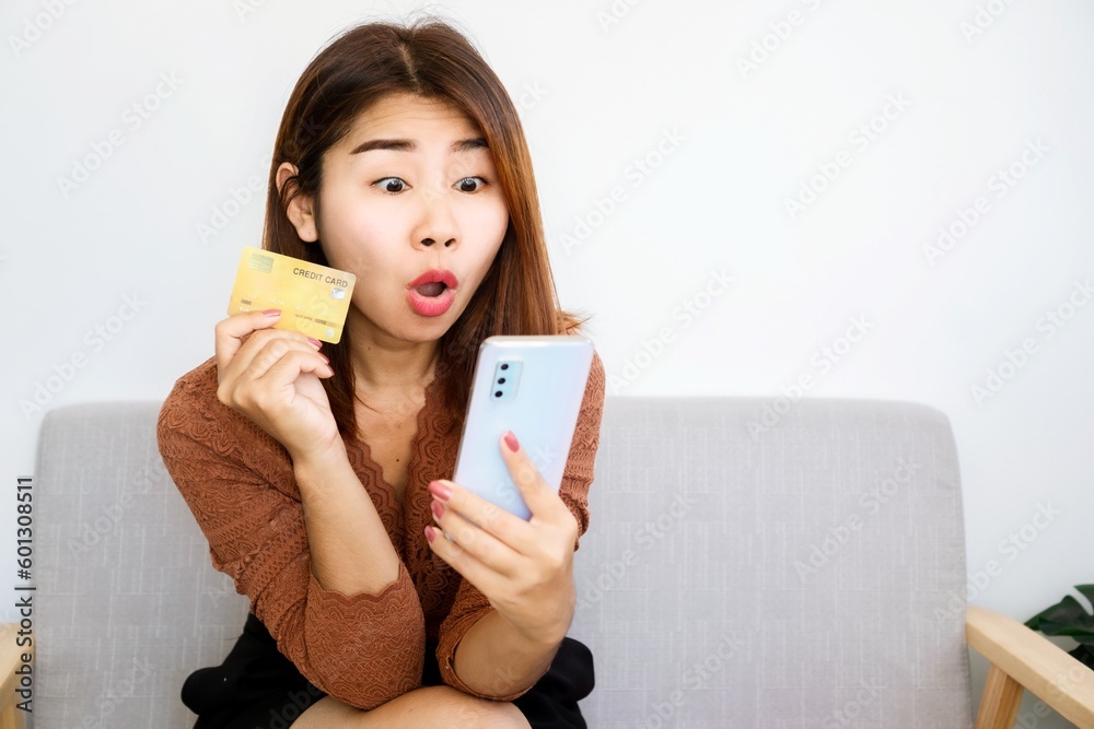 excited shopaholic Asian woman ready to pay for sale products hand holding credit card and mobile phone excited shopaholic Asian woman ready to pay for sale products hand holding credit card and mobile phone