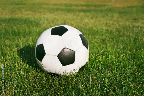 Classic soccer ball, typical black and white pattern, placed on the spot of stadium turf. Traditional football ball on the green grass field of arena.