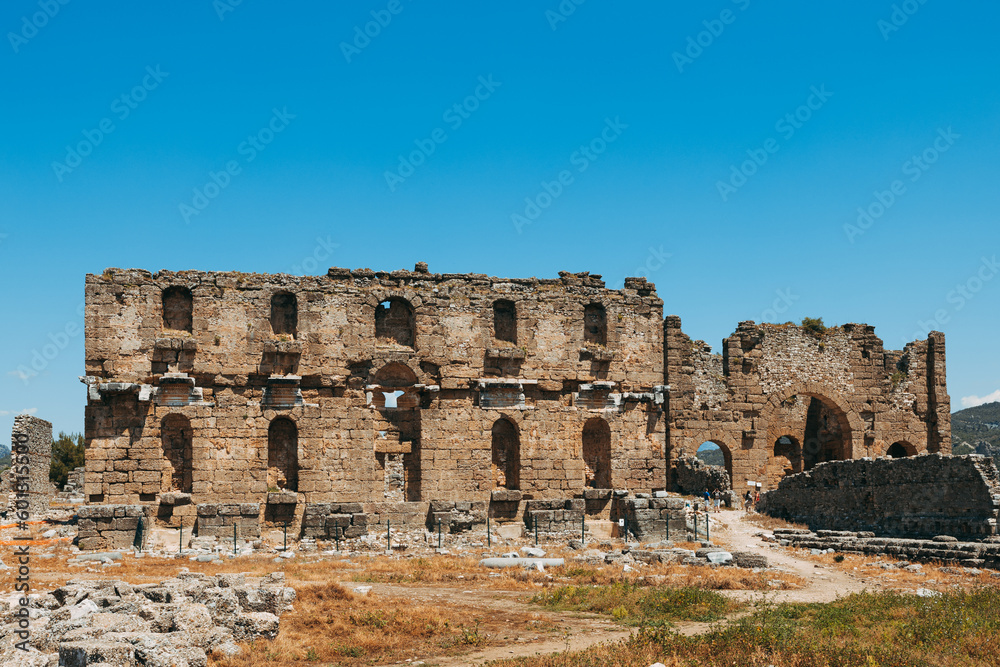 Aspendos archaeological site featuring the well-preserved amphitheater and arches, buildings in Side, Antalya, Turkey.