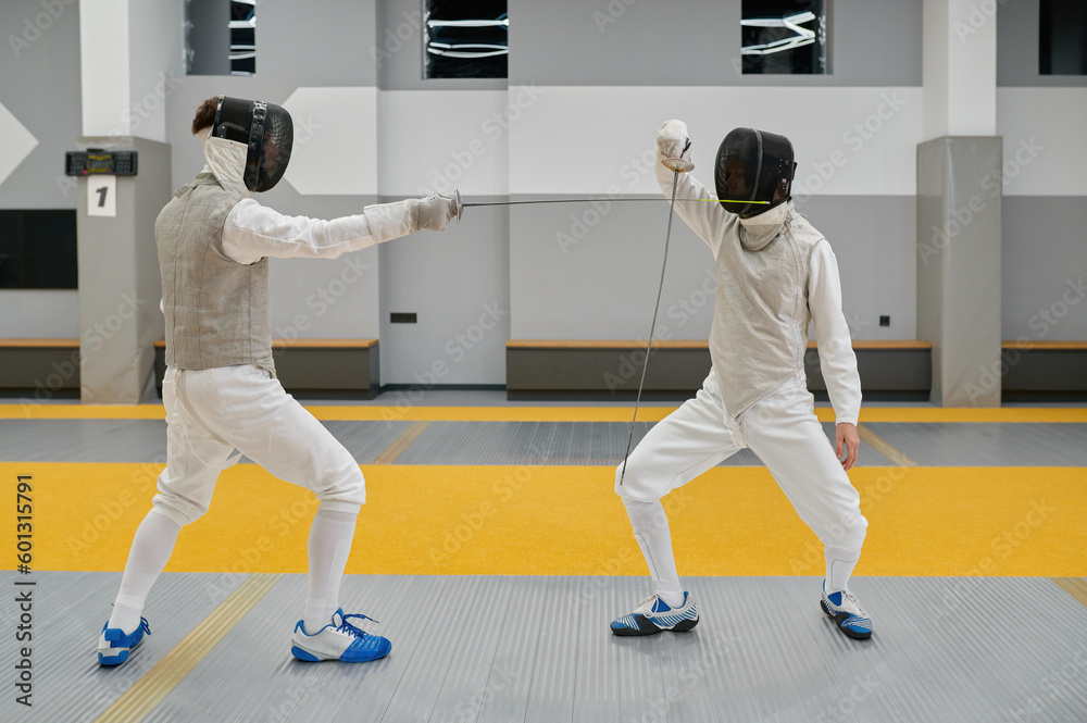 Two swordsmen exercising and fighting with rapiers during fencing competition