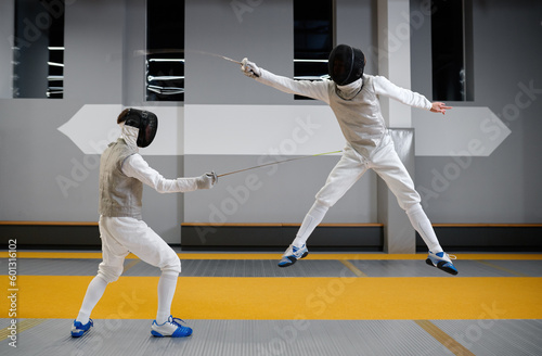Two fencers sparring during training session in professional martial art school
