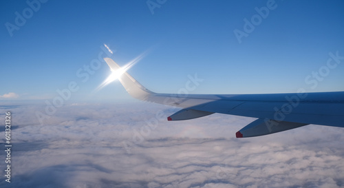Airplane in flight. People travelling.  Aerial view from plane window.  Blue sky above clouds.