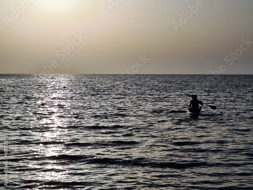 evocative image of the silhouette of people on an inflatable board at sunset on the sea