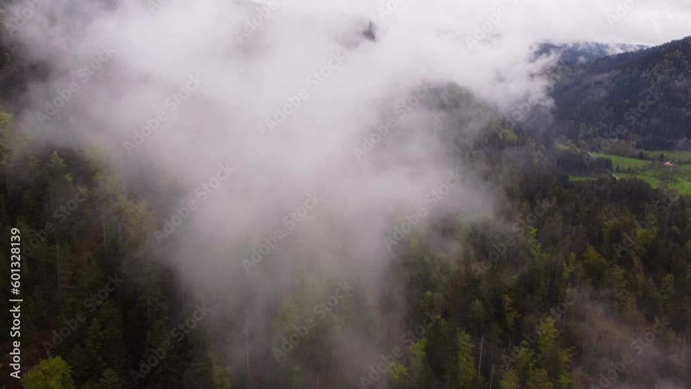 Drone slow fly through white clouds over a moody forest mountain valley during spring time Drone slow fly through white clouds over a moody forest mountain valley during spring time