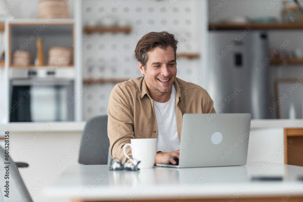 A man sitting at the dining table, typing on his laptop and drinking morning coffee. A man sitting at the dining table, typing on his laptop and drinking morning coffee.