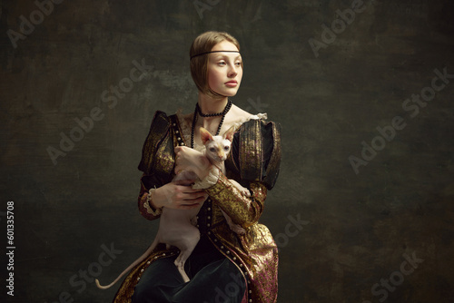 Portrait of beautiful young girl in elegant clothing over dark vintage background posing with sphynx cat. Lady with ermine remake. Concept of history, renaissance art remake, comparison of eras