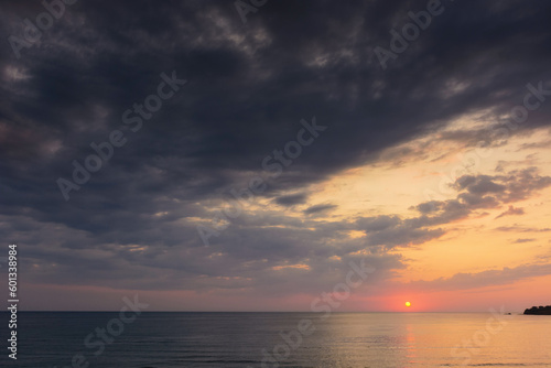dramatic dawn at the sea. gray clouds on the sky with red sun above the horizon. summer holidays rainy weather forecast