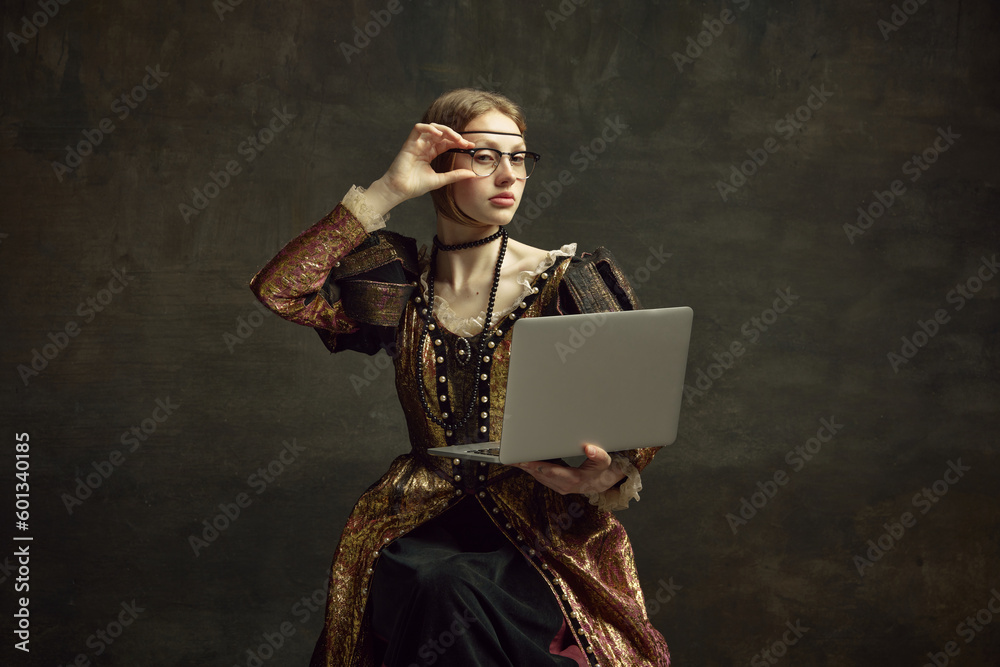 Portrait of young girl, royal person, princess in vintage dress and modern glasses working on laptop against dark green background. Concept of history, renaissance art remake, comparison of eras - obrazy, fototapety, plakaty 