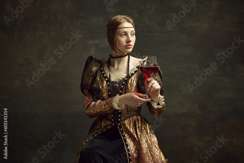 Portrait of pretty, young girl, princess in vintage dress drinking red wine against dark green background. Celebration, degustation. Concept of history, renaissance art remake, comparison of eras