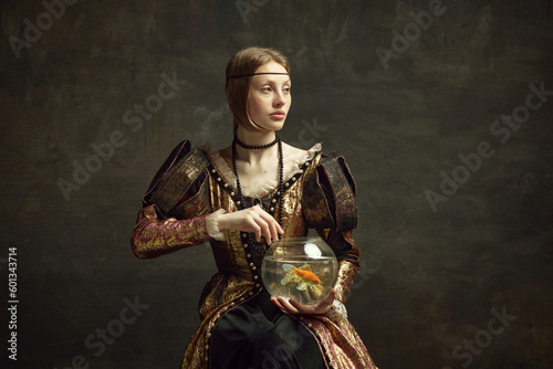 Portrait of royal person, young girl in vintage dress holding large aquarium against dark green background. Concept of history, renaissance art remake, comparison of eras