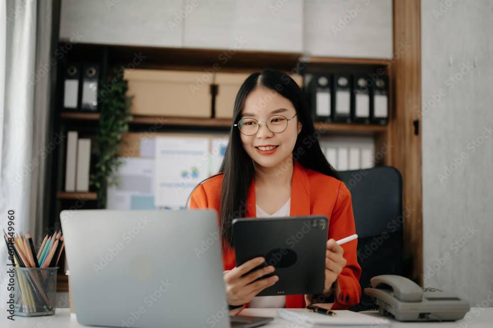 Asian businesswoman working in the office with working notepad, tablet and laptop documents in office.