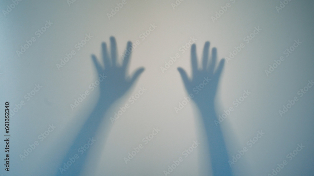 Shadow Blur of a horror man behind frosted glass. Blurred hand, body shape abstraction and one palm. Reflection of the silhouette through the light. Ghost silhouette behind the glass. Defocused shot