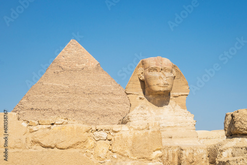 A closeup of the face of the Great Sphinx with pyramid in the background on a beautiful blue sky day in Giza, Cairo, Egypt. copy space