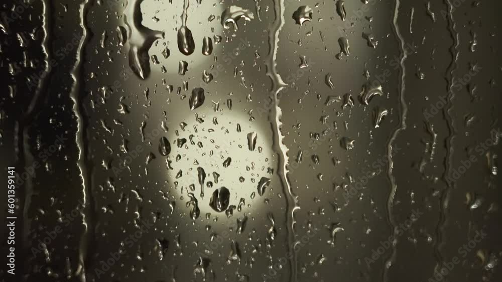 Drops of water flow on the window at night