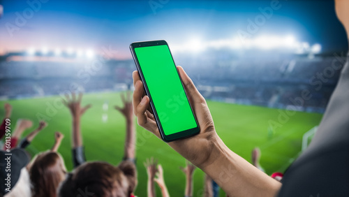 Sport Stadium Championship: Person\'s Hand Holding Green-Screen Chroma Key Smartphone. Sports Match with Fans on Tribune Cheering for Favourite Team to Win. Isolated POV Close-up Copyspace Template.