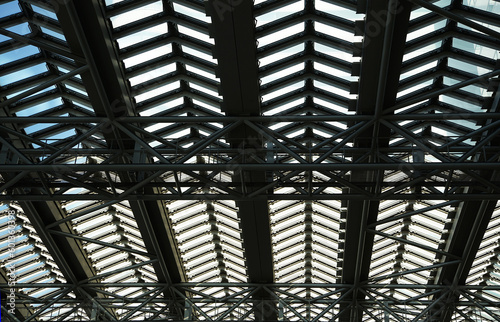 Blue sky seen from the steel frame and glass roof of a building