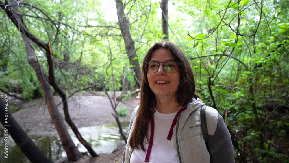 Caucasian woman smiling to camera near stream in the forest. Handheld medium shot Caucasian woman smiling to camera near stream in the forest. Handheld medium shot