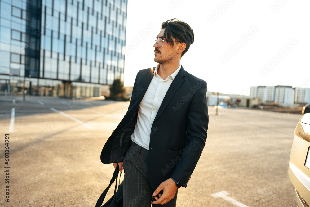 Portrait of confident attractive businessman in suit looking at camera near office building
