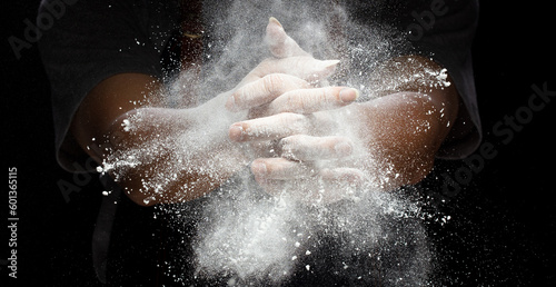Chef prepare white flour dust for cooking bakery food. Elderly man Chef clap hand, white flour dust explode fly in air. Flour stop motion in air with freeze high speed shutter, black background © Jade