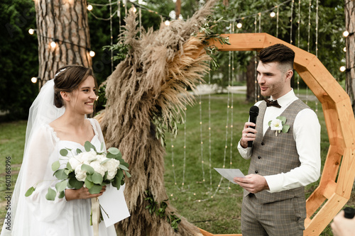 A handsome groom makes an oath to the bride at the wedding ceremony. wedding ceremony outside. nesta with the groom on the background of the wedding arch photo