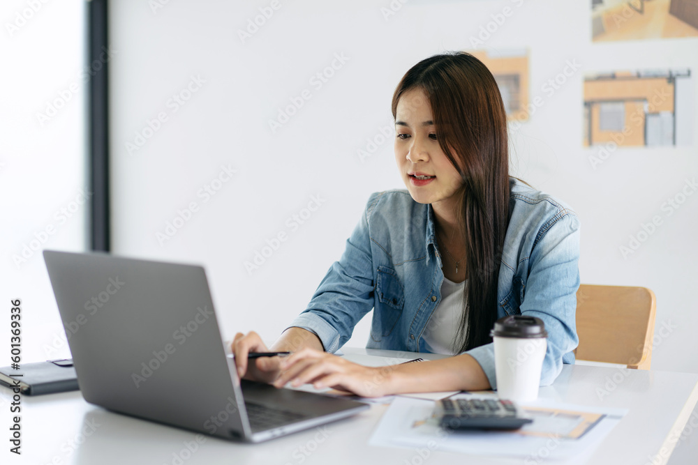 Woman architect typing data on laptop for sketching and designin Woman architect typing data on laptop for sketching and designin