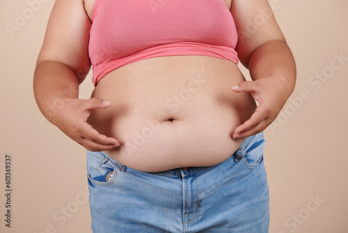 she wants to lose weight concept of abdominal fat surgery., the girl takes extra fat on sides of her stomach with her hand. isolate on white background, Type with increased fat deposition and fullness © nareekarn