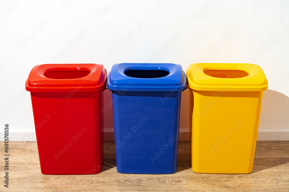 Three plastic trash bins against the wall in the building Three plastic trash bins against the wall in the building