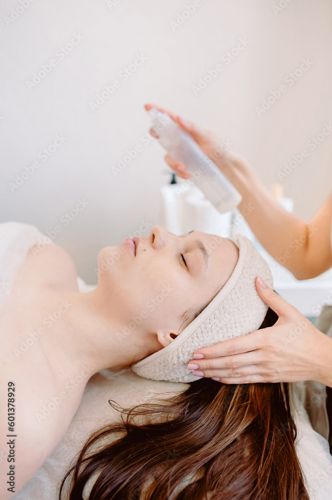 Naklejka premium Close-up of a beautician doing facial beauty treatments or treatment for female clients in the field of aesthetic medicine. Cosmetology concept.vertical photo