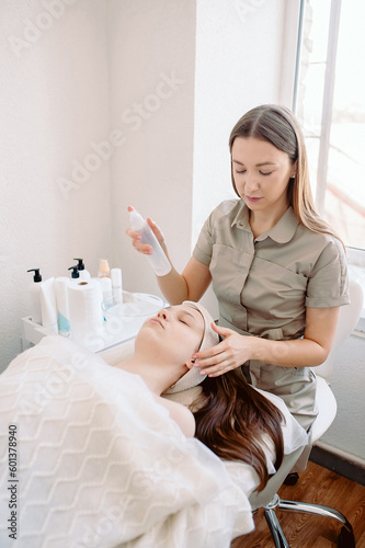 A professional beautician performs a deep cleansing of the client s face. Front view  vertical frame