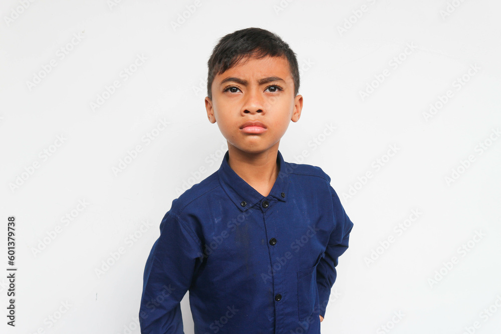 Angry boy wearing a blue shirt looking at the camera with serious face. Isolated on white background Angry boy wearing a blue shirt looking at the camera with serious face. Isolated on white background