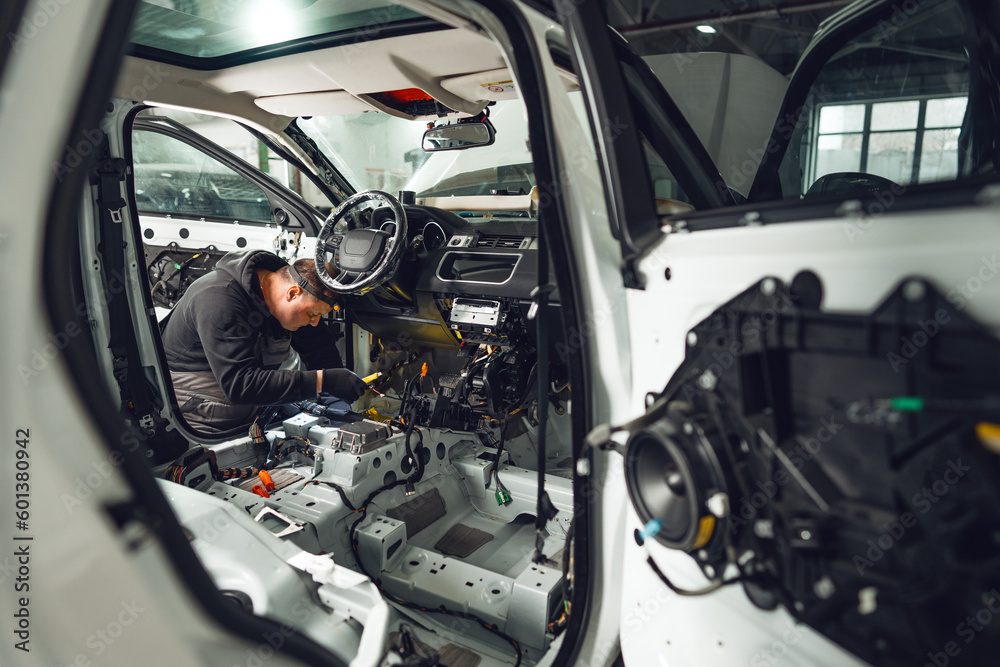 Obraz premium Car service worker installing noise insulation soundproofing in the car
