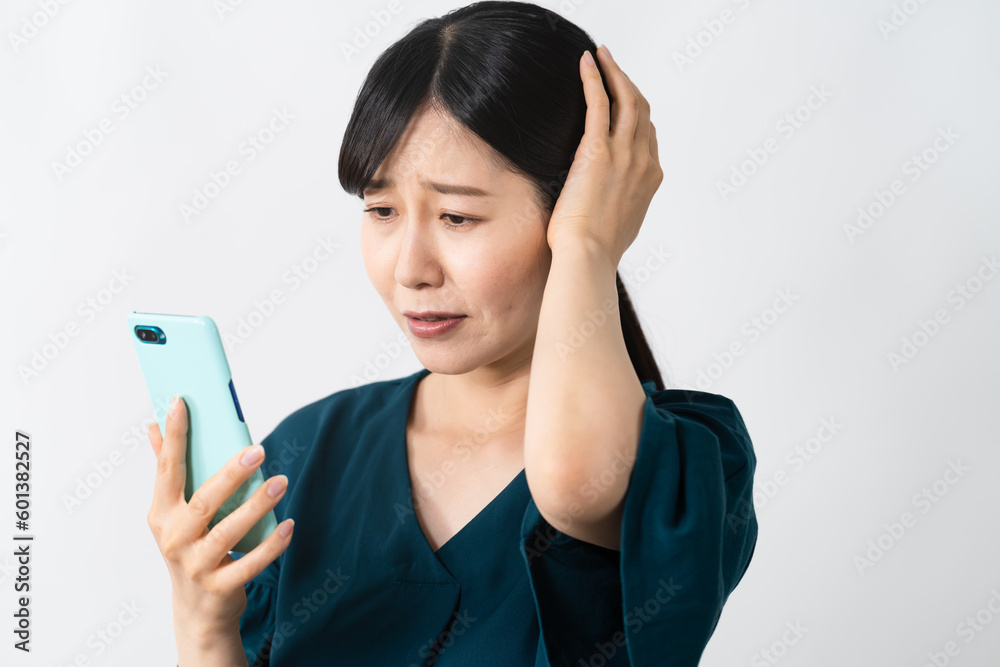スマートフォンを持ちながら頭を抱える若い女性