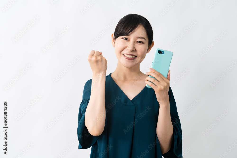 スマートフォンを持ちながらガッツポーズをする若い女性