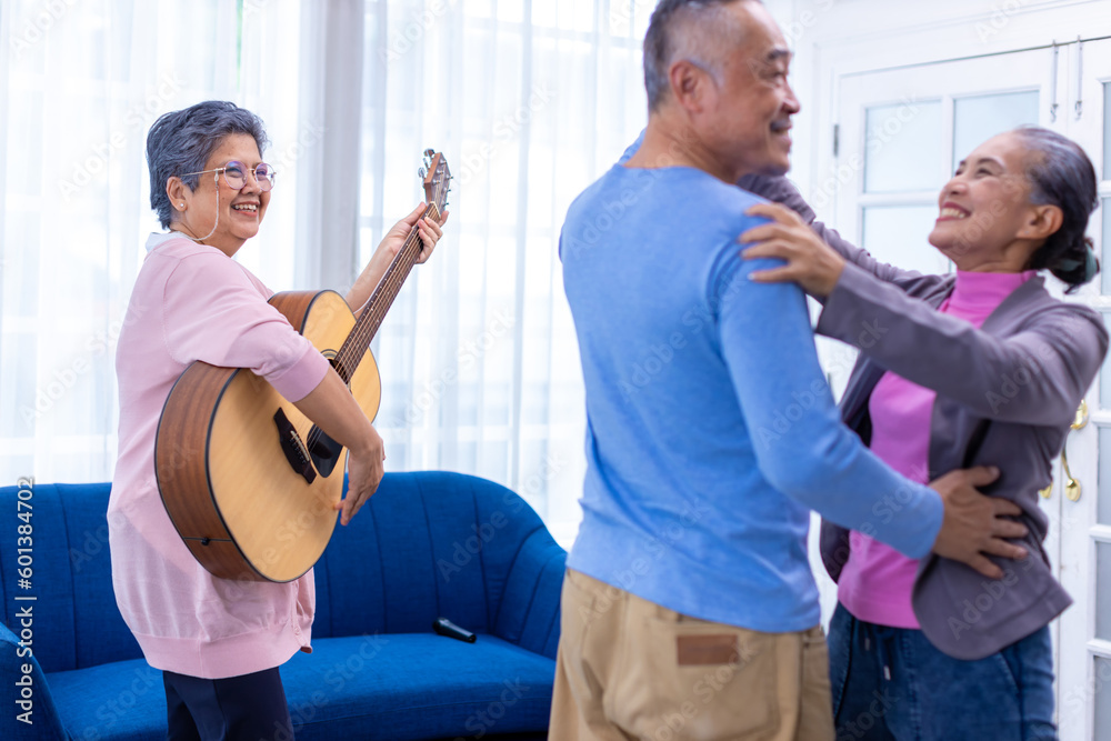 Obraz premium Senior friends on party dancing and playing guitar at home. Elderly musician at party has fun with cheerful family singing together. Leisure activity of Asian Senior.