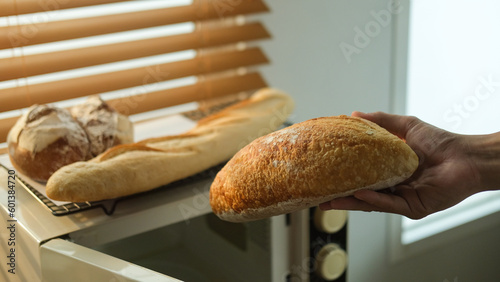 Closeup view of baker hand holding fresh rustic organic bread from the oven.