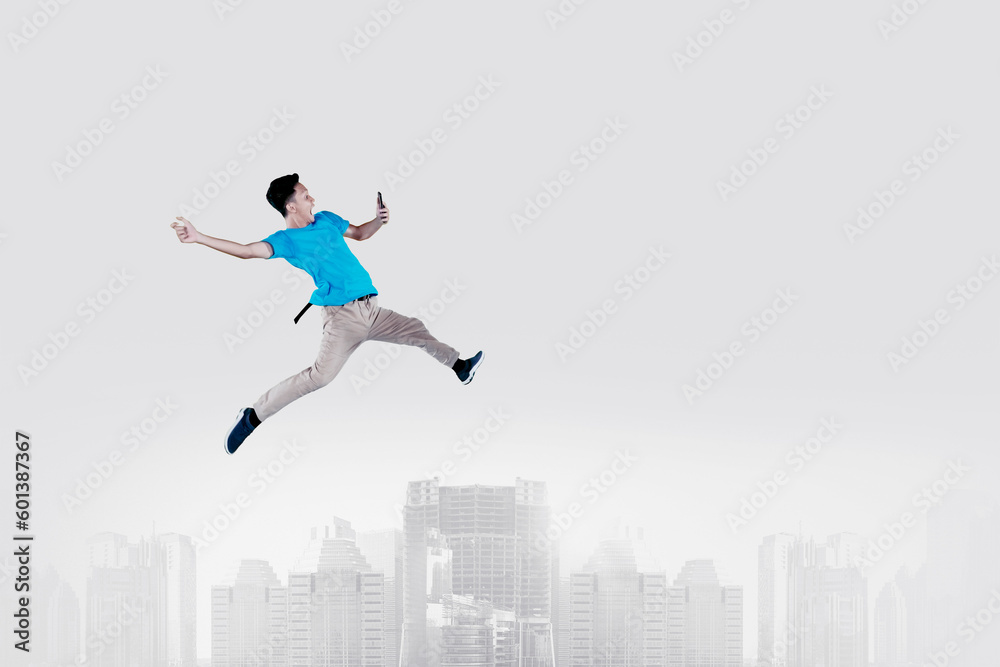 Excited jumping young man looking at mobile phone collage Excited jumping young man looking at mobile phone collage