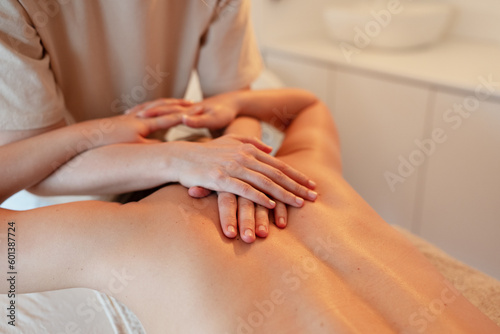 Body massage treatment. Woman having massage in the spa salon. Masseur working on his back.	